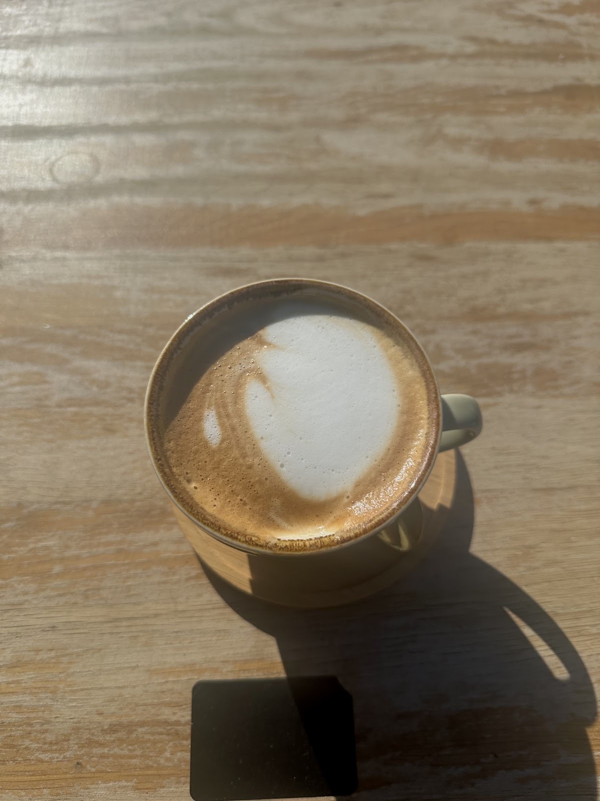 A flat white with heart latte art in a plain white cup
