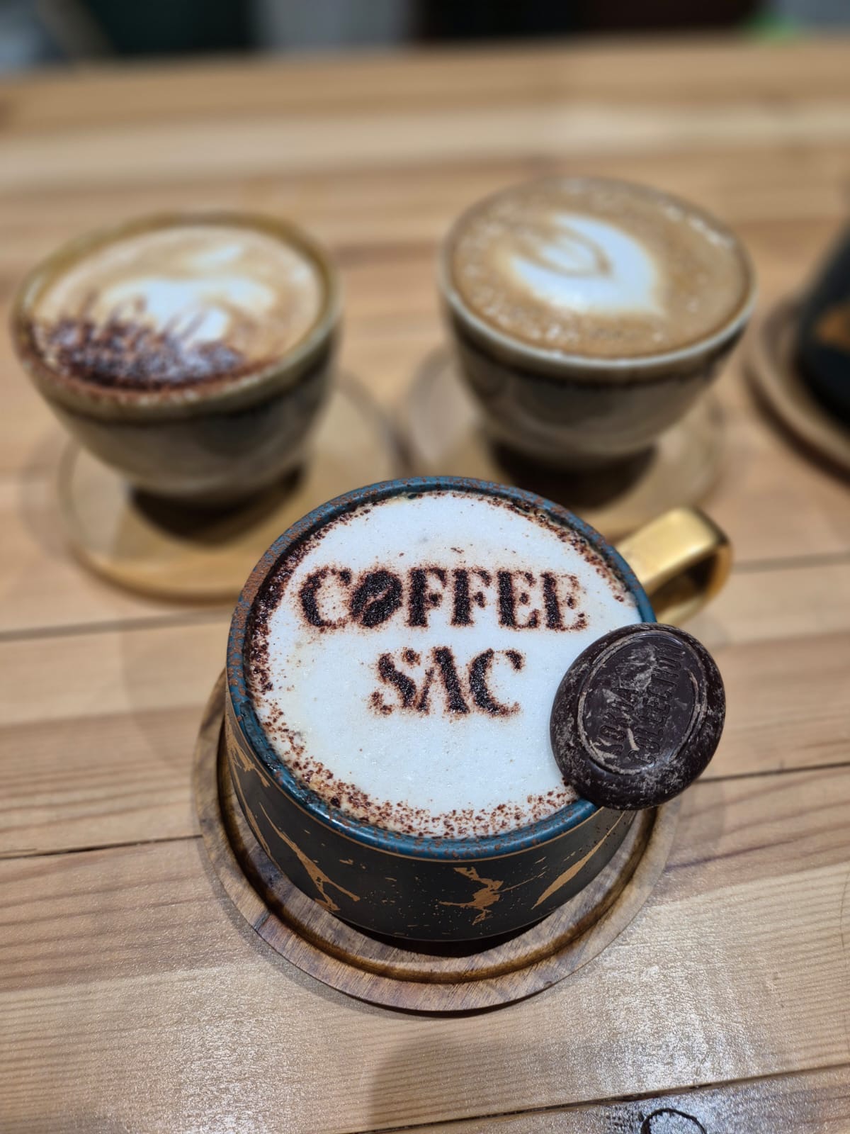 A stencilled cocoa-dusted coffee with a chocolate coin on the saucer