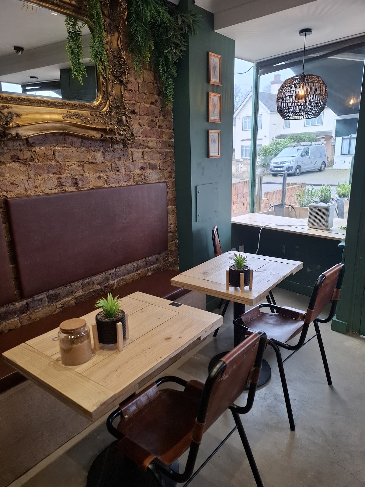 A window table for two with leather chairs, exposed brick and a gold mirror